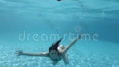 一个十几岁的女孩在清澈的水<strong>里</strong>在游<strong>泳池里</strong>游泳和<strong>玩耍</strong>。 吹泡泡，看着镜头..